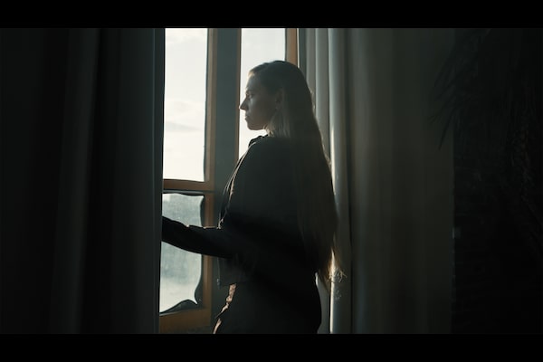 Immagine di esempio di una donna che guarda al paesaggio fuori da una finestra, con il suo contorno visto in controluce tra due tende