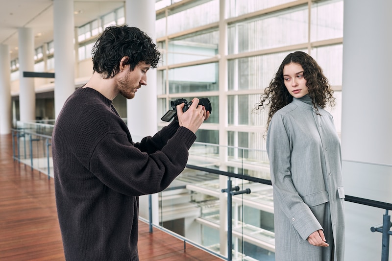 Immagine di utilizzo di un videografo che tiene in mano una fotocamera α7R VI e riprende una donna mentre la segue.